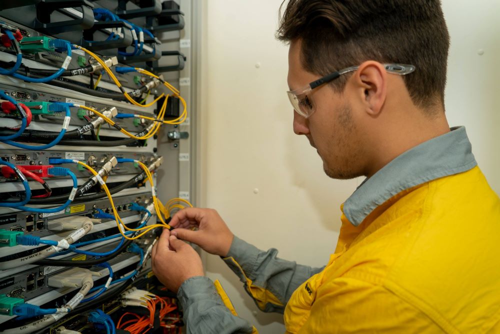 Apprentice crew member working on communications switches