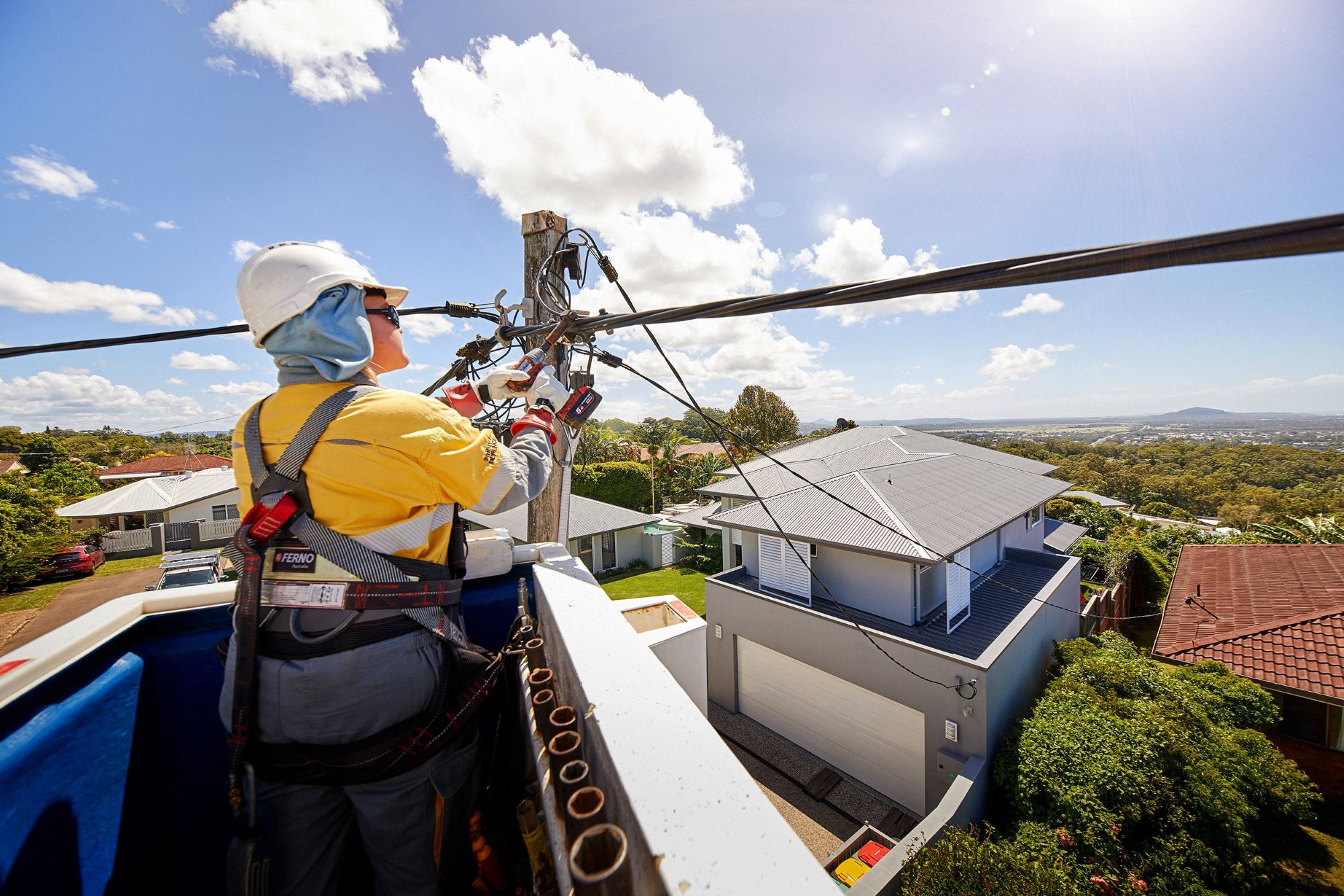 Power worker repairing overhead powerline from a bucket truck overlooking a residential area