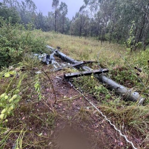 Power pole on the ground with damaged wires in bush