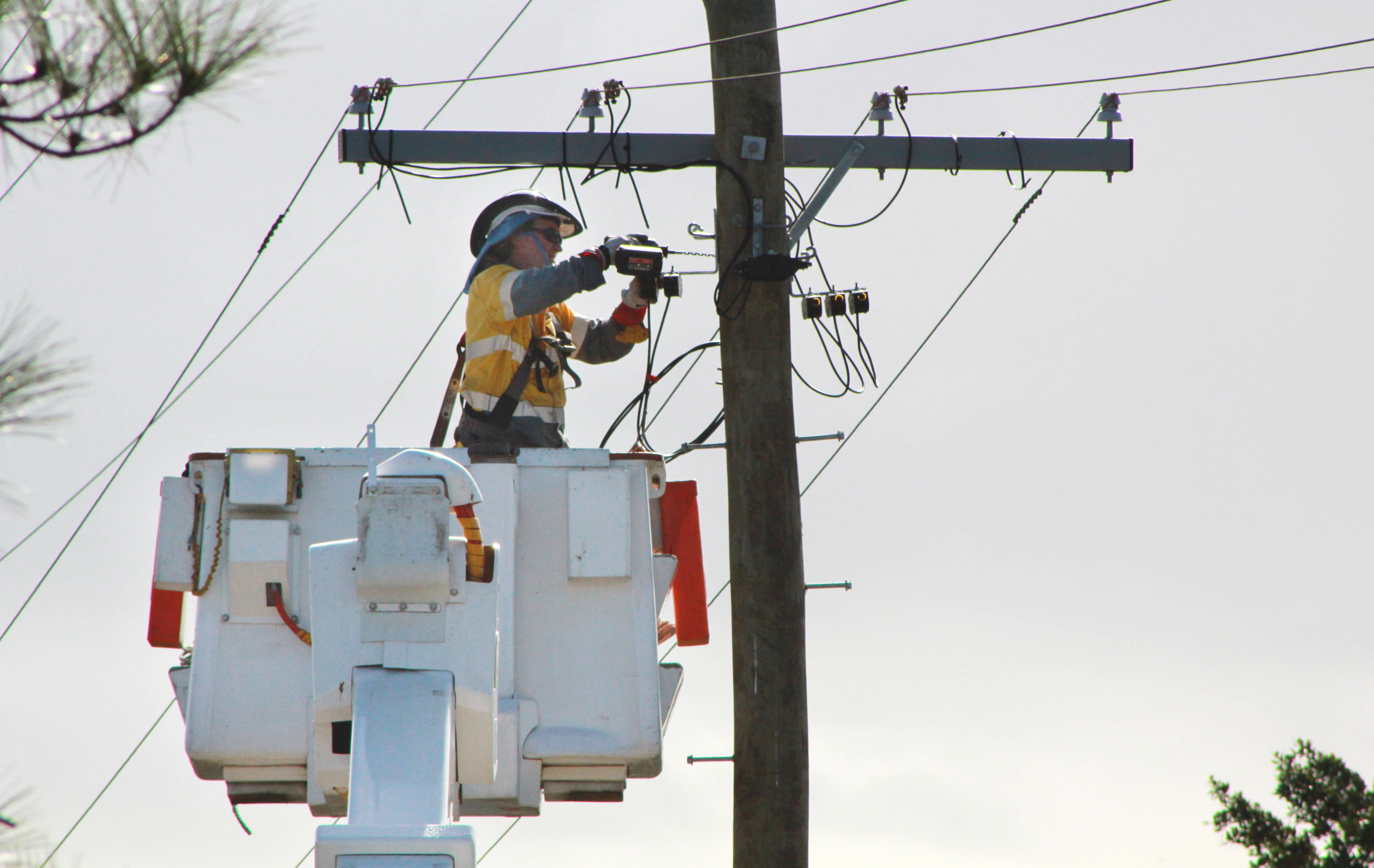 Worker in cherry picker working on powerlines